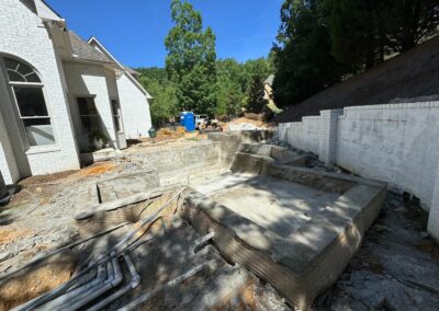 Pool under construction, showing the shell and the retaining wall up the slope