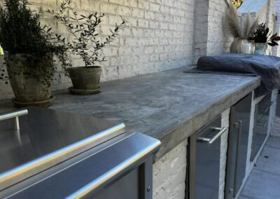 Outdoor kitchen at Greystone Dream with concrete counter, stainless cabinetry and a wall-mounted screen